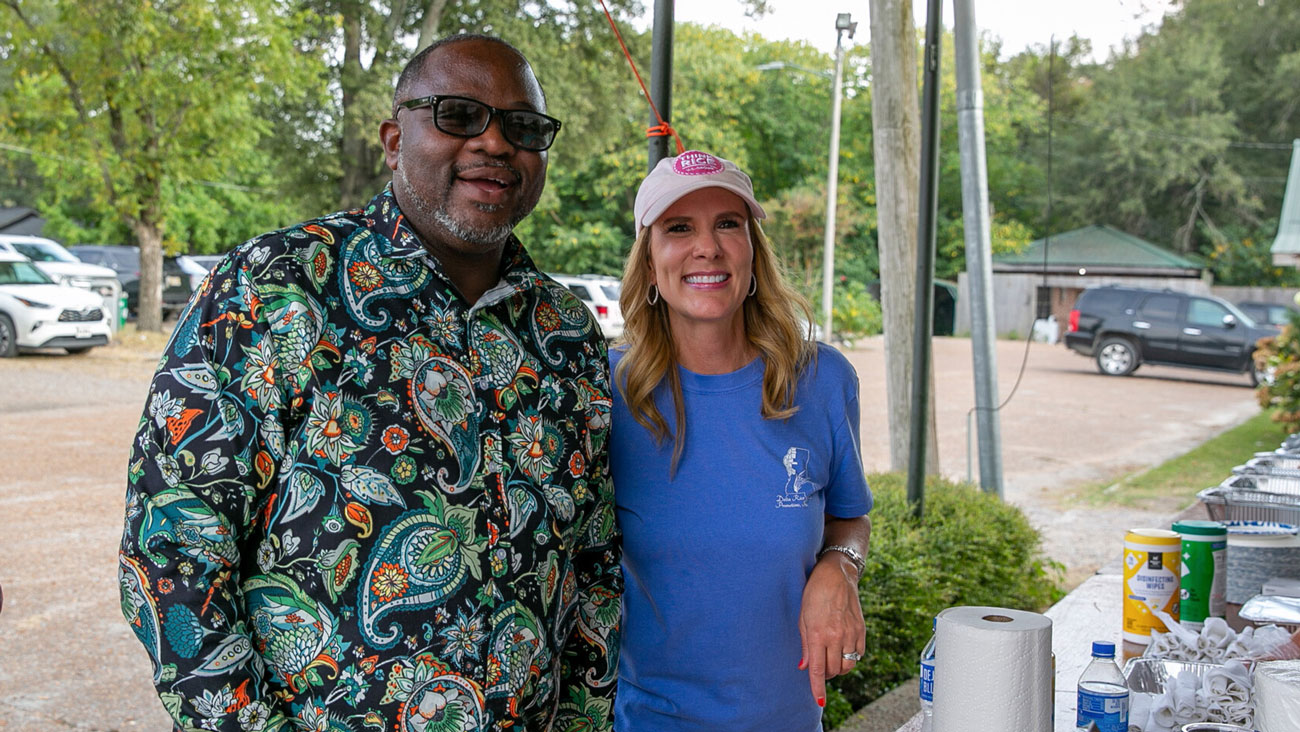 A man and woman stand smiling together.