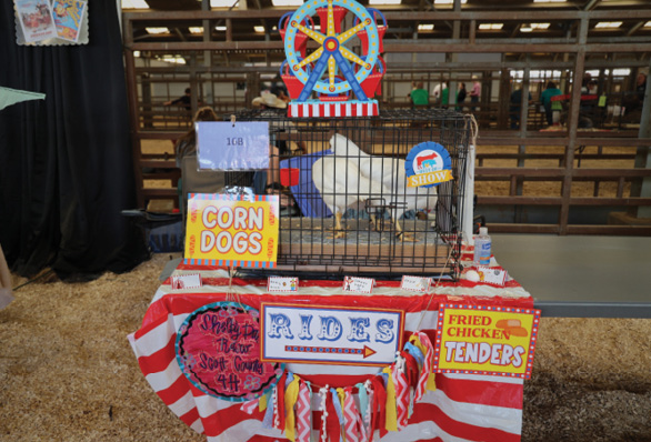 The coop is designed like a circus with many signs. The signs include "Fried Chicken Tenders," "Corn Dogs," "Rides" and others.