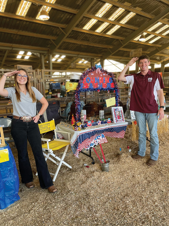 Two judges stand by a decorated American-themed coop.