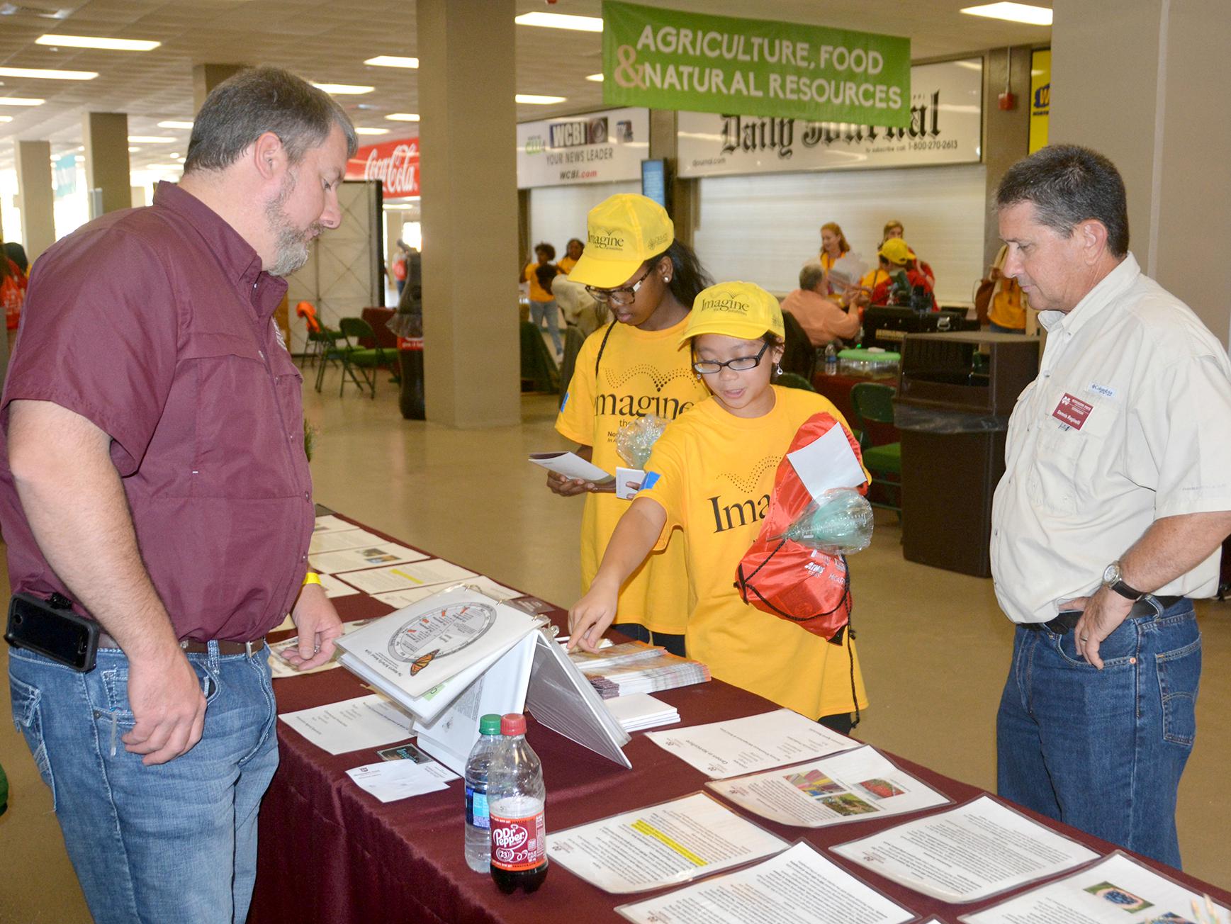 Monroe County Extension agent Randall Nevins, left, reviews horticulture career options with Karen Carothers and Elsie Buskes, both of Oxford, Mississippi. Dennis Reginelli, right, a regional specialist with the Mississippi State University Extension Service, joins the discussion at a career expo for eighth-graders in Tupelo, Mississippi, on Oct. 5, 2016. (Photo by MSU Extension Service/Linda Breazeale)