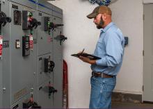 A man stands in front of a control panel.