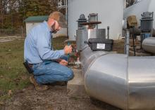 A man adjusts a valve on a water pipe.