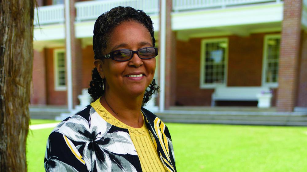 Woman in glasses smiles in front of brick building