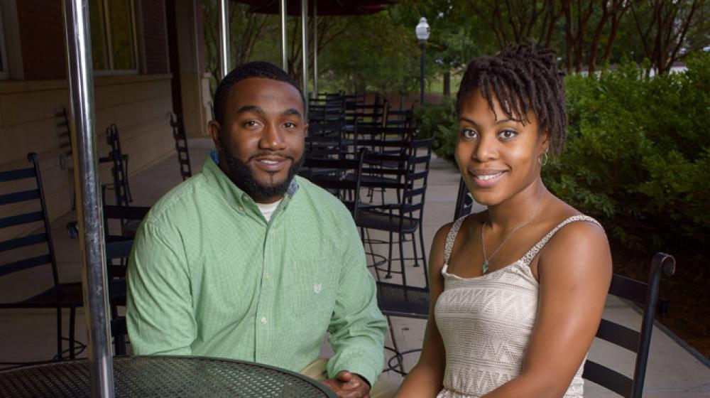 Man in green dress shirt sits at a table with a woman in a white dress