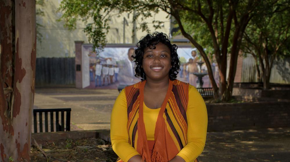 Shandrea Jenkins sitting on a brick planter.