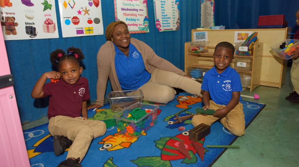 A woman smiling with two smiling children.