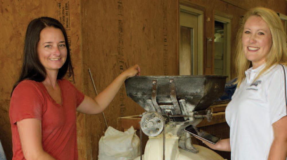 Two women stand on either side of a machine.