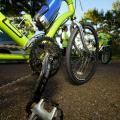 A close up shot of the gears and bottom of a fluorescent green bike parked in a parking lot.