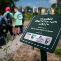A sign marking the entrance to the Heritage Demonstration Garden with children standing in the background.