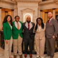 Five people, including two teens in green 4-H blazers, smile for a group photo.