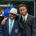 Two boys, wearing suits and fedoras, smiling.