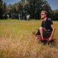 A keeling man wearing glasses and a kilt, holding an archery bow.