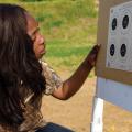 A young woman kneels down next to a board with targets.