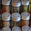 Rows of spices in clear jars with silver tops. 