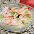 A bowl of salad with shrimp on top. 