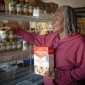 A woman puts nonperishable food on pantry shelves.