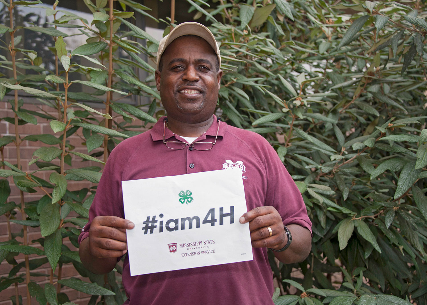 A man holding a sign in front of his chest that says “#iam4H.”