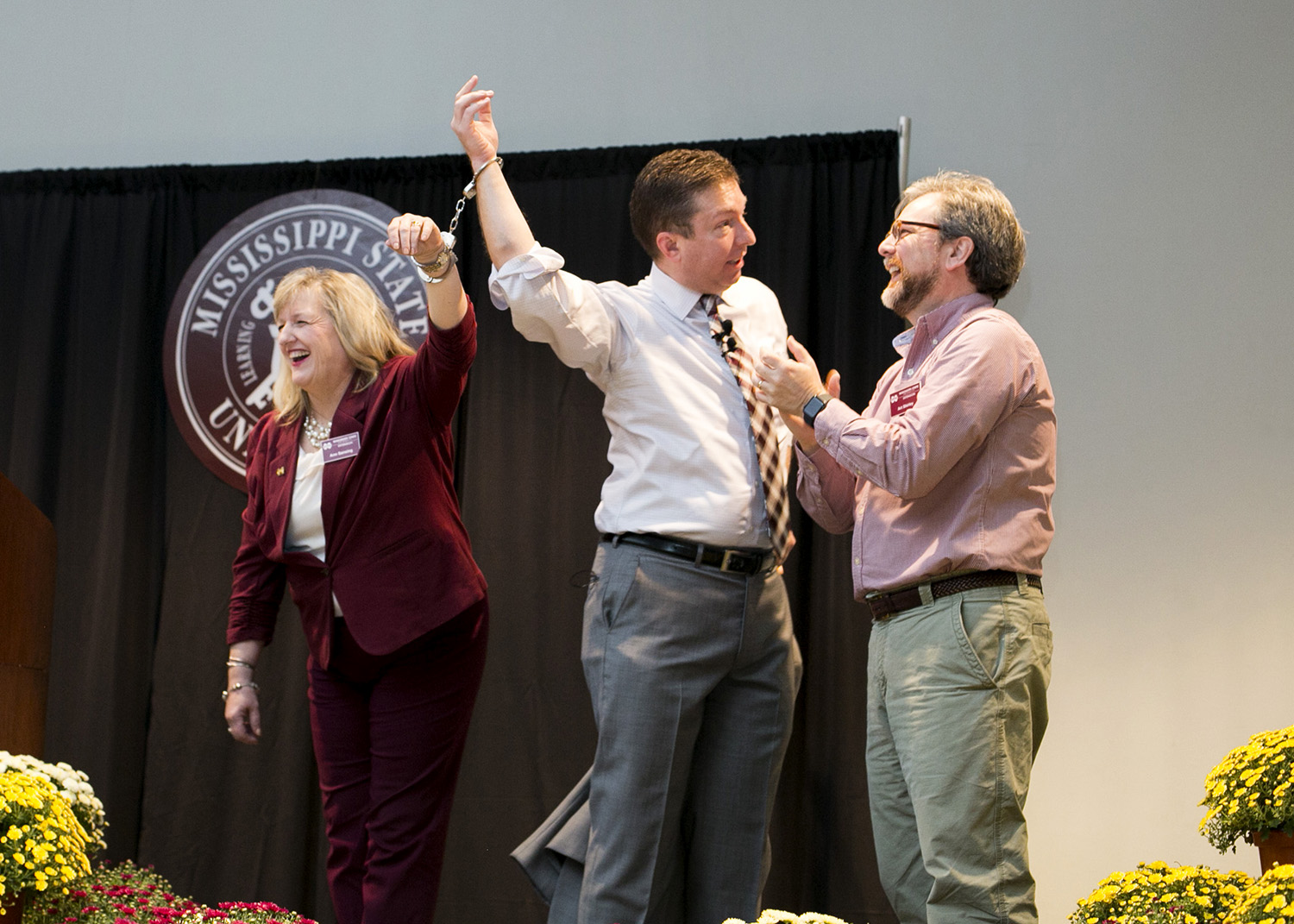 Three adults participate in a magic trick involving escapism. 