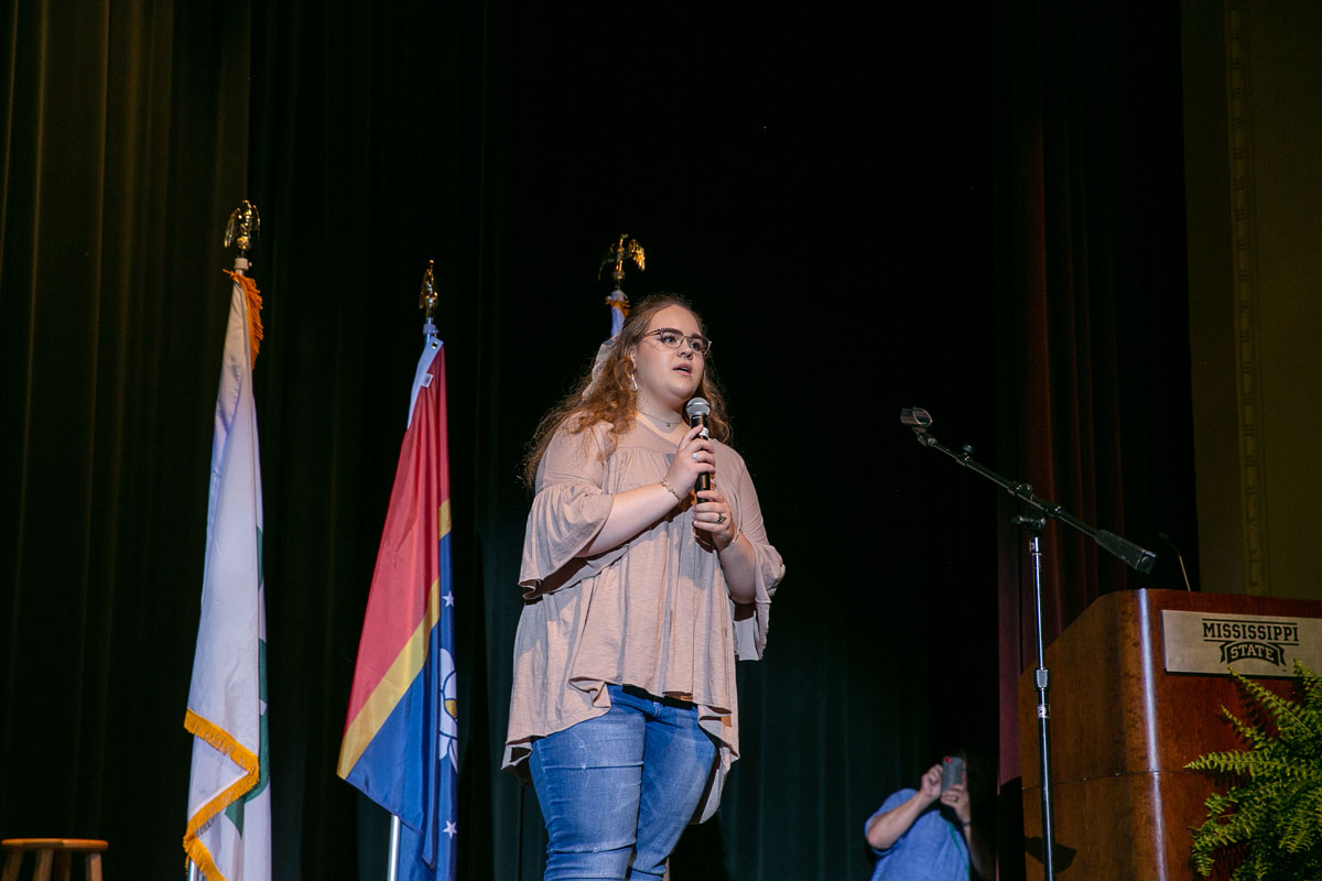 A teenage girl singing into a microphone.