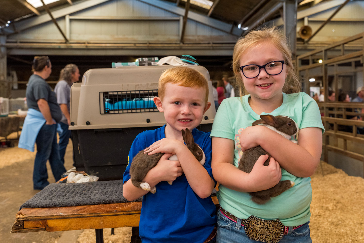 A boy and a girl, each holding a dark rabbit, smiling.