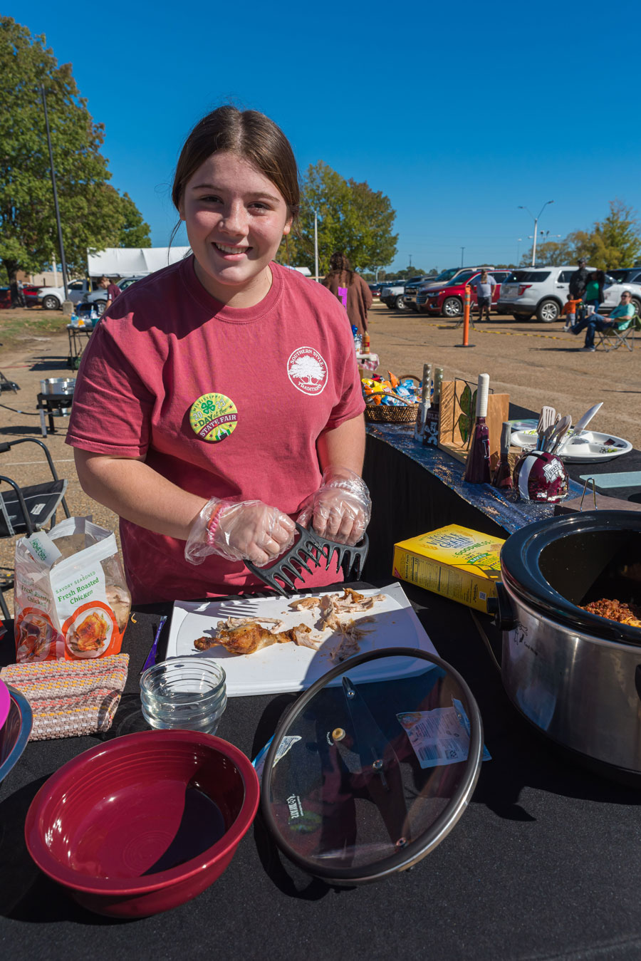 A girl, holding meat shredders, smiles.