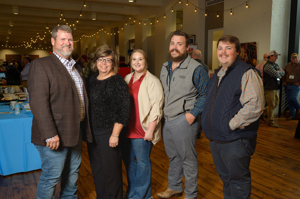 A group of five people standing in a line and smiling.