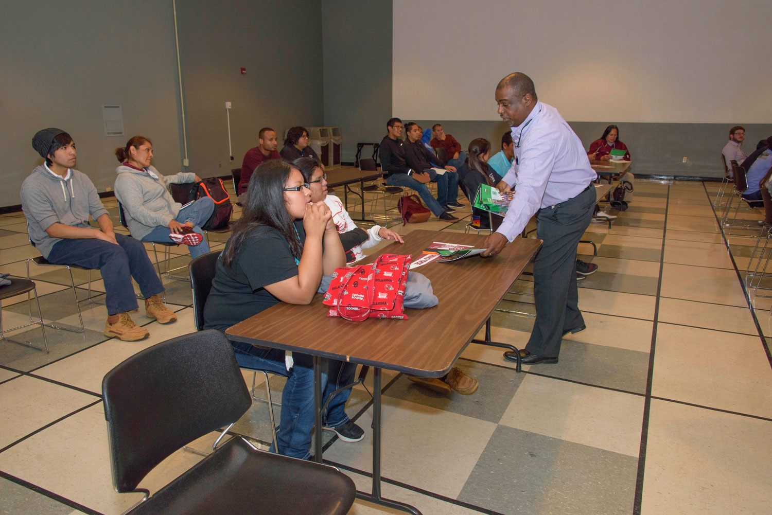 A man distributes 4-H booklets to a group of seated teens.