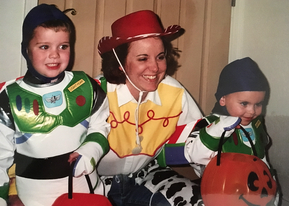 Children in Disney Halloween costumes pose for a photo with a female relative who is also wearing a costume. 