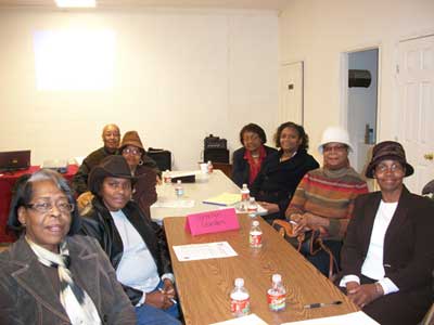 Eight people posing around a cluttered brown table.