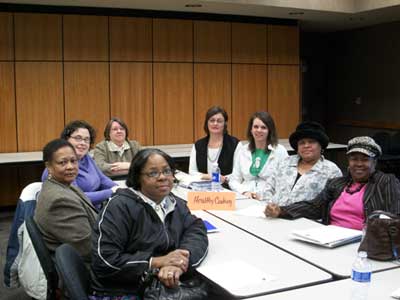 Eight women gathered at a table pose for a picture.