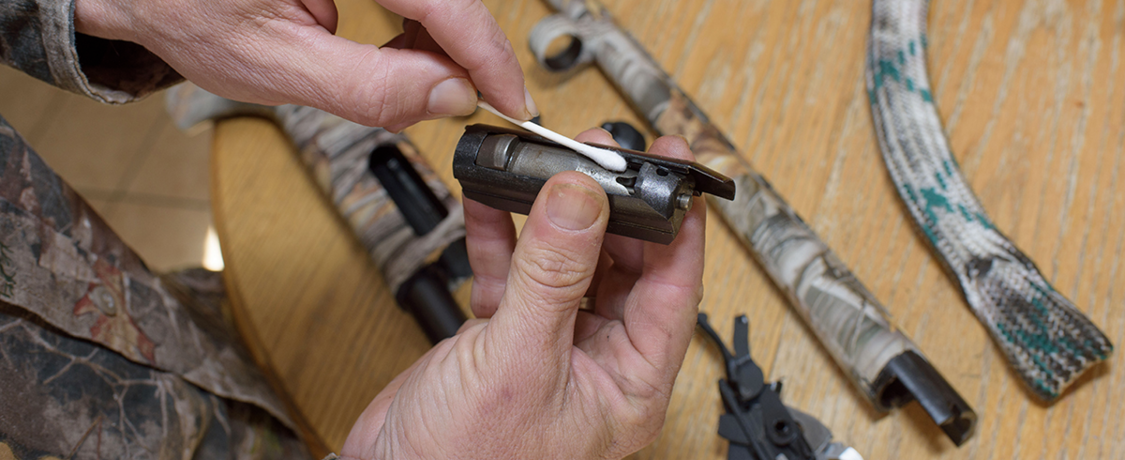 Cleaning a gun part with a cotton swab.