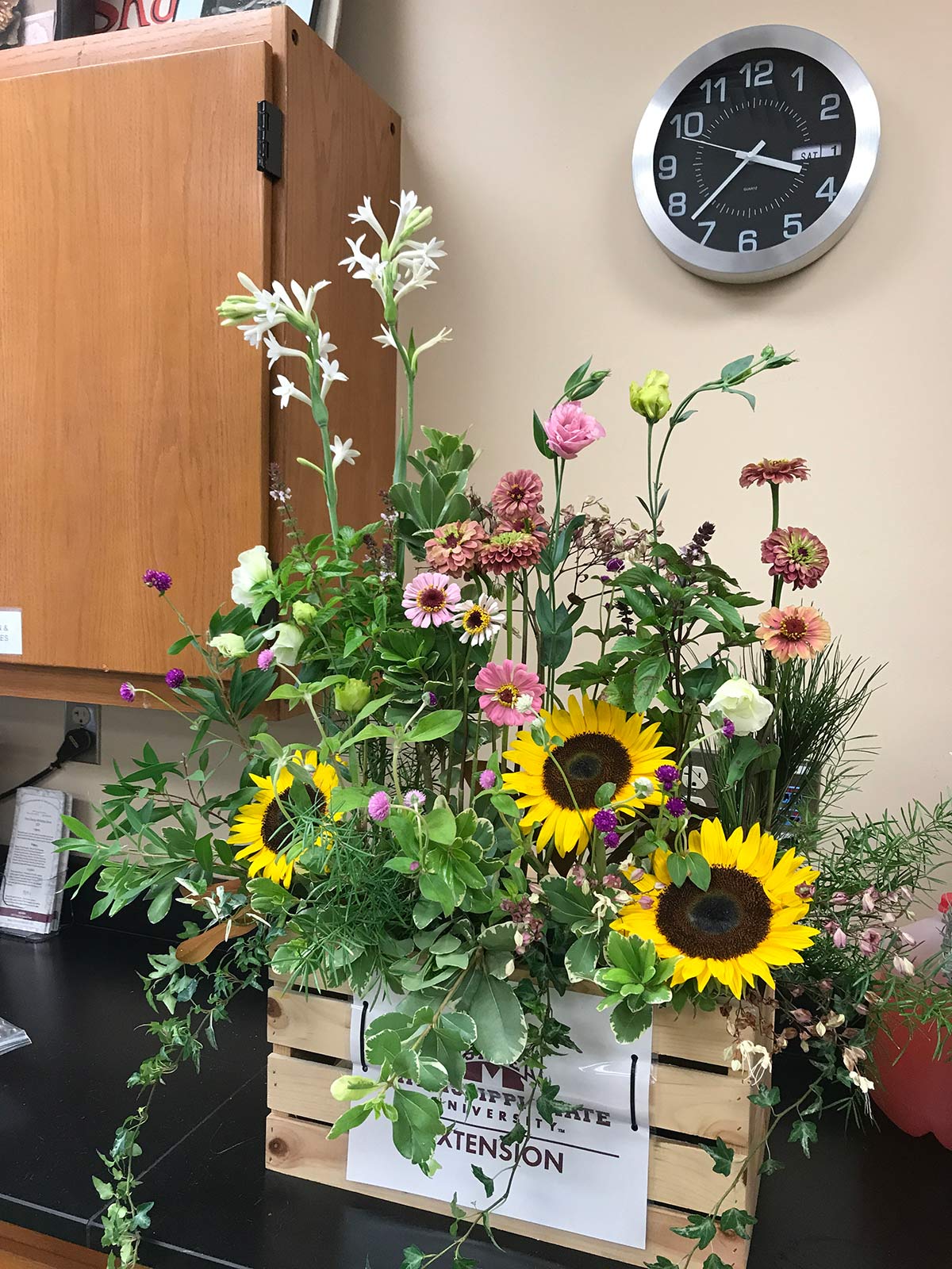 An arrangement of flowers of varying heights on a decorative crate. 