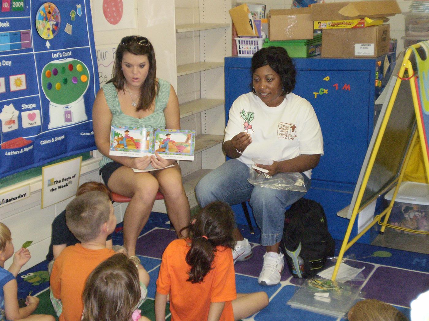 Mississippi State University health promotion graduate student Katie Shumpert and nutrition undergraduate student Latossia Clark show preschoolers examples of nutritious fruits and vegetables. (Photo by Chiquita Briley/MSU Department of Food Science, Nutrition and Health Promotion)