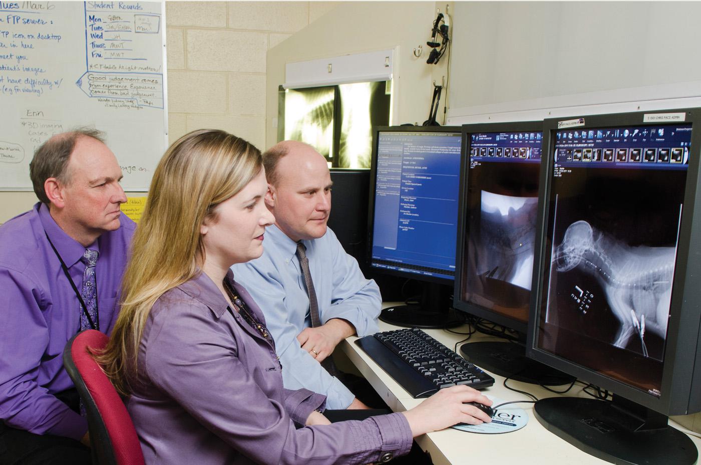 Drs. Andrew Mackin, Erin Brinkman and Todd Archer (from left) study pre- and post-procedural images of a tracheal stent patient at Mississippi State University's College of Veterinary Medicine. (Photo by MSU College of Veterinary Medicine/Tom Thompson)