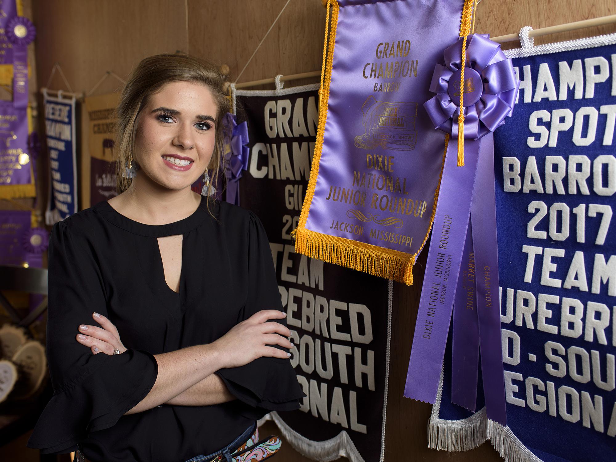 A woman stands in front of several award ribbons.