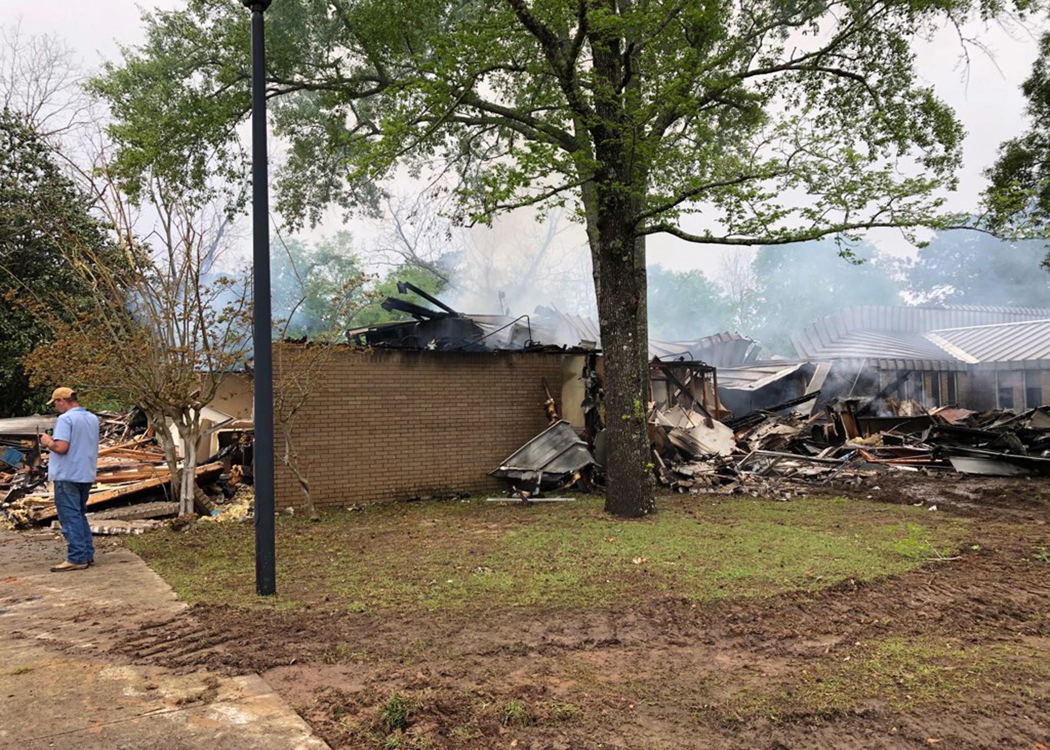 Smoke rises from a mostly burned structure.