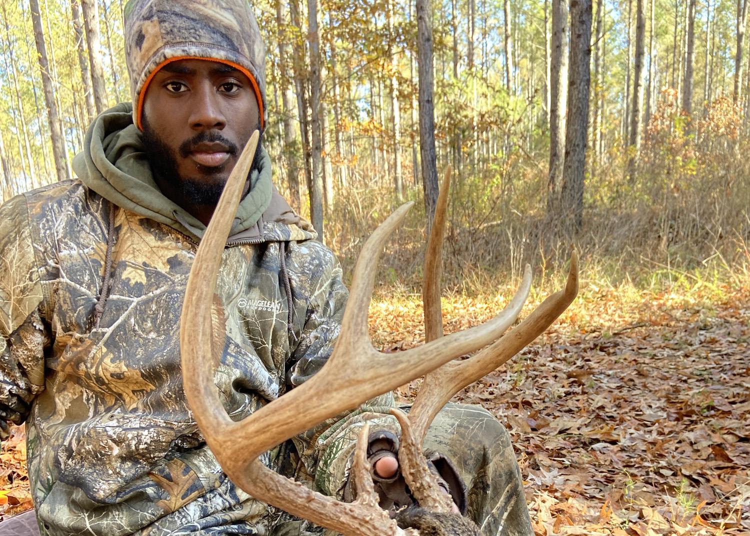 A man kneels beside a harvested buck.