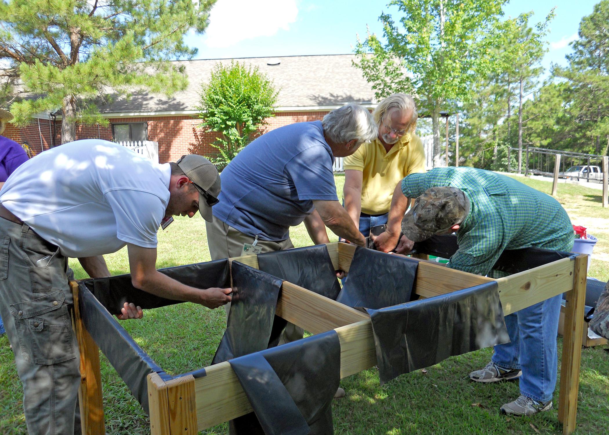 From left, Lamar County Extension Agent Ross Sadler, Pine Belt Master Gardener Paul Cavanaugh, Lamar County Technical Center teacher and volunteer Ken McCoy and Pine Belt Master Gardener intern Cecil Chambliss prepare a handicapped-accessible raised bed for plants. The group built two beds for residents of The Windham House of Hattiesburg, an assisted-living facility for seniors on May 28 and will return monthly to help with the beds and teach workshops. (Photo by MSU Ag Communications/Susan Collins-Smith)