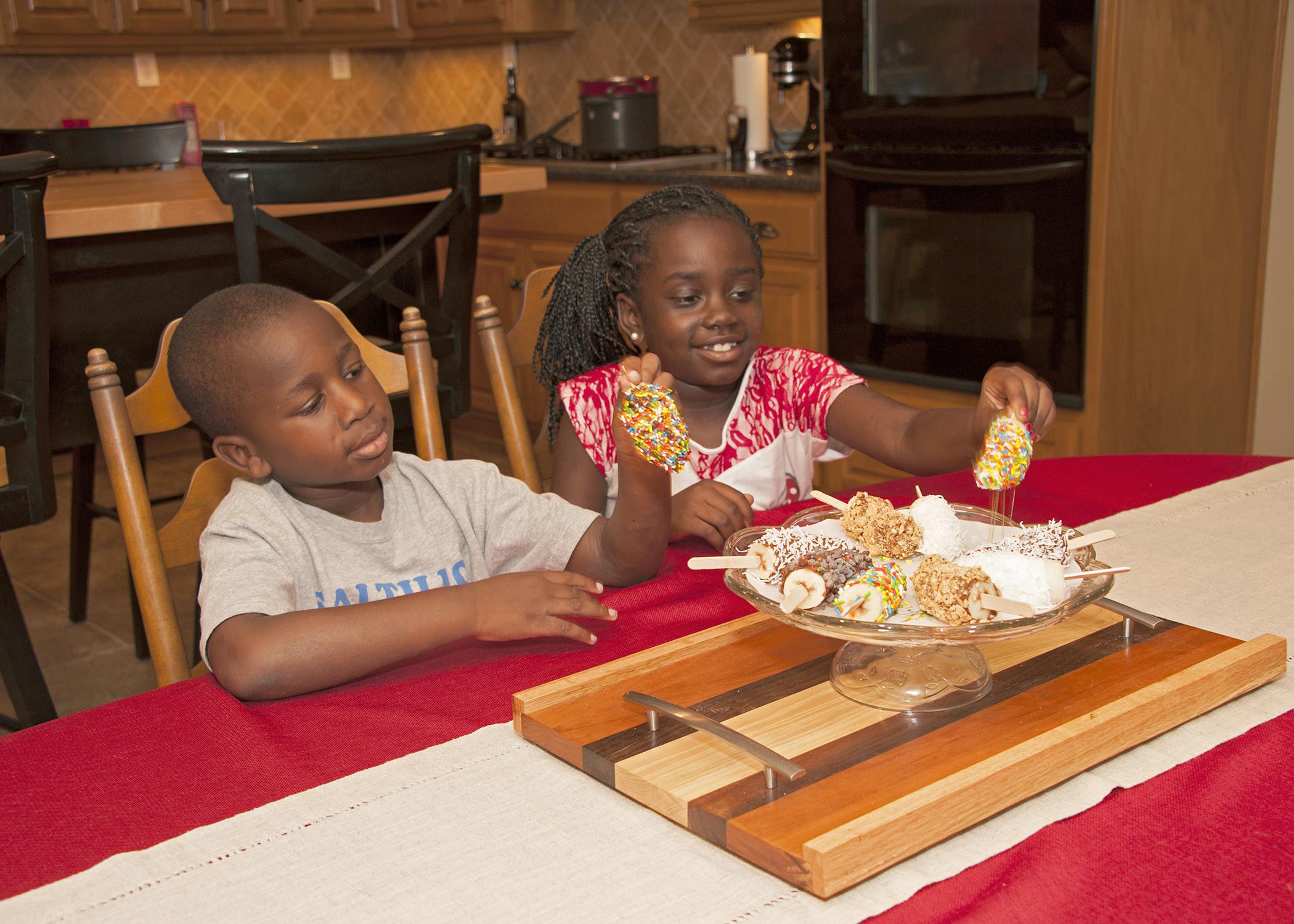 Six-year-old Jordan Ross and 8-year-old Nyema Johnson of Columbus enjoy choosing fun summer treats -- frozen banana pops dipped in either vanilla yogurt or almond bark. (Photo by MSU Ag Communications/Kat Lawrence)