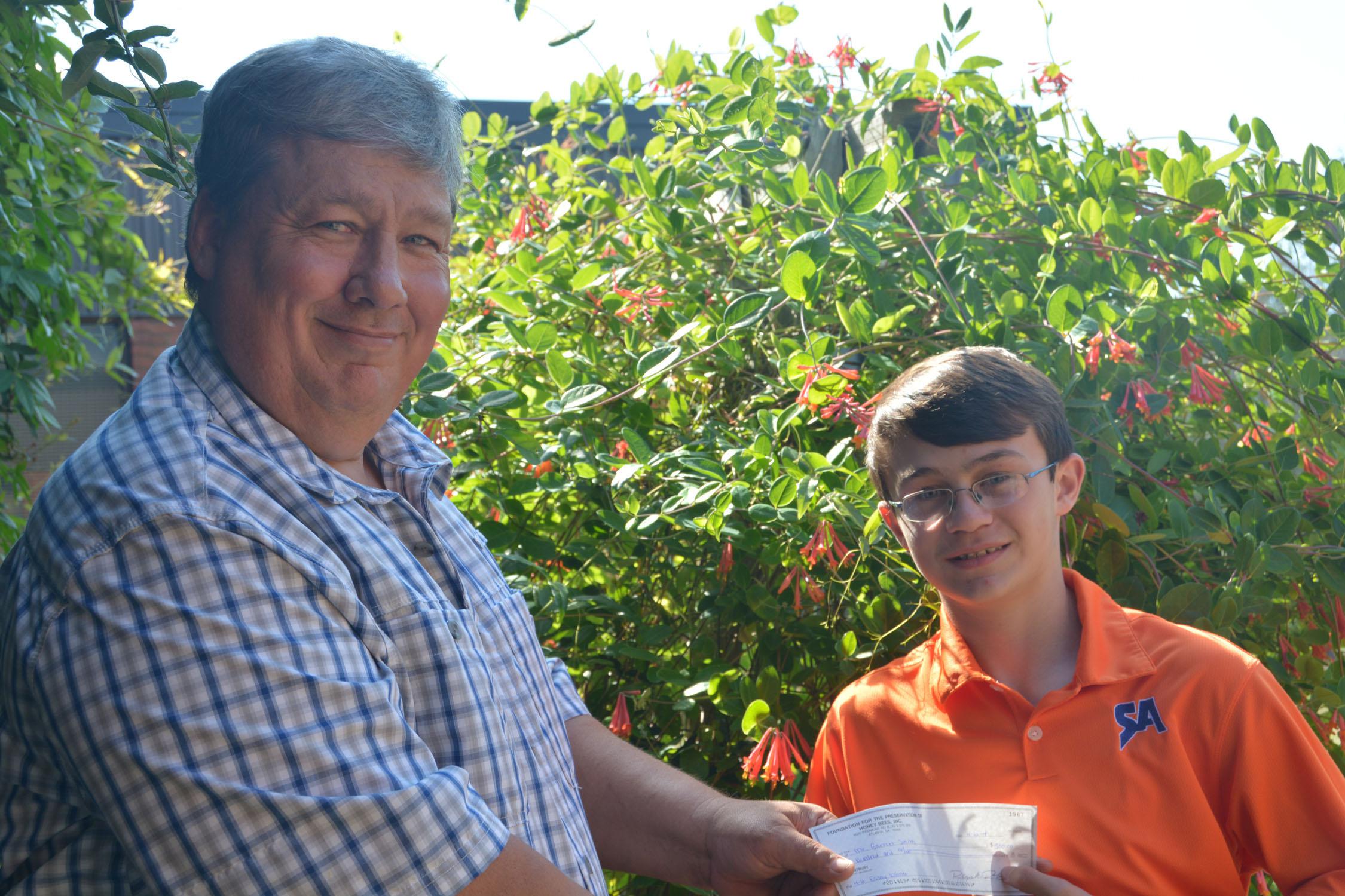 Mississippi State University Extension Service beekeeping specialist Jeff Harris presents 4-H'er Garrett Smith of Starkville, Miss. with the state- and national-level awards for the 4-H Honey Bee Essay Contest. The presentation was made May 7, 2014 at MSU. (Photo by MSU Ag Communications/Keri Collins Lewis)