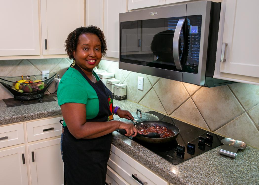 A woman stirs cranberry turkey meatballs cooking on the stove.