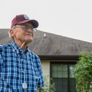 A man wearing a Mississippi State University baseball hat smiles into the distance.