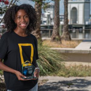 A young woman smiling and holding a trophy.