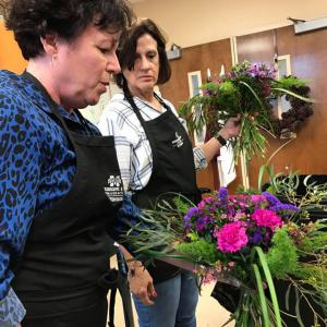 Two women viewing floral bouquets they have made.  