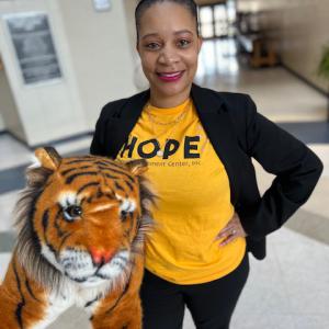 A woman wearing a black dress jacket and a yellow shirt listing “HOPE.”