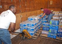 B.J. McClenton, Monroe County Extension director (left), and Charlie Stokes, area Extension agent (right), unload water from a semi-trailer to distribute to tornado victims in Monroe County. MSU Extension Service employees are storing and distributing supplies to those affected by the April 26 and 27 tornadoes. (Photo by Scott Corey)