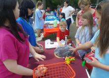 Volunteer teenagers use a prop resembling the human brain to demonstrate brain function to children.