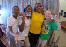 Four fourth-grade girls show off their personal identification cards that are passes to federal parks.