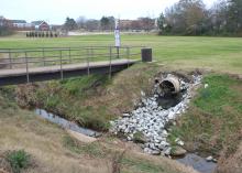 A drainage pipe, with stones leading to the creek bed, emptying into Catalpa Creek. 