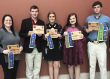 Five people stand in a row holding their awards. 